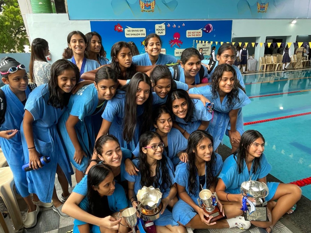 Swim team with trophies on the pool deck